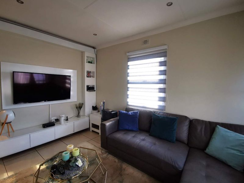 A comfortable living room featuring tiled flooring, recessed downlights, and a custom built-in media unit with integrated shelving.