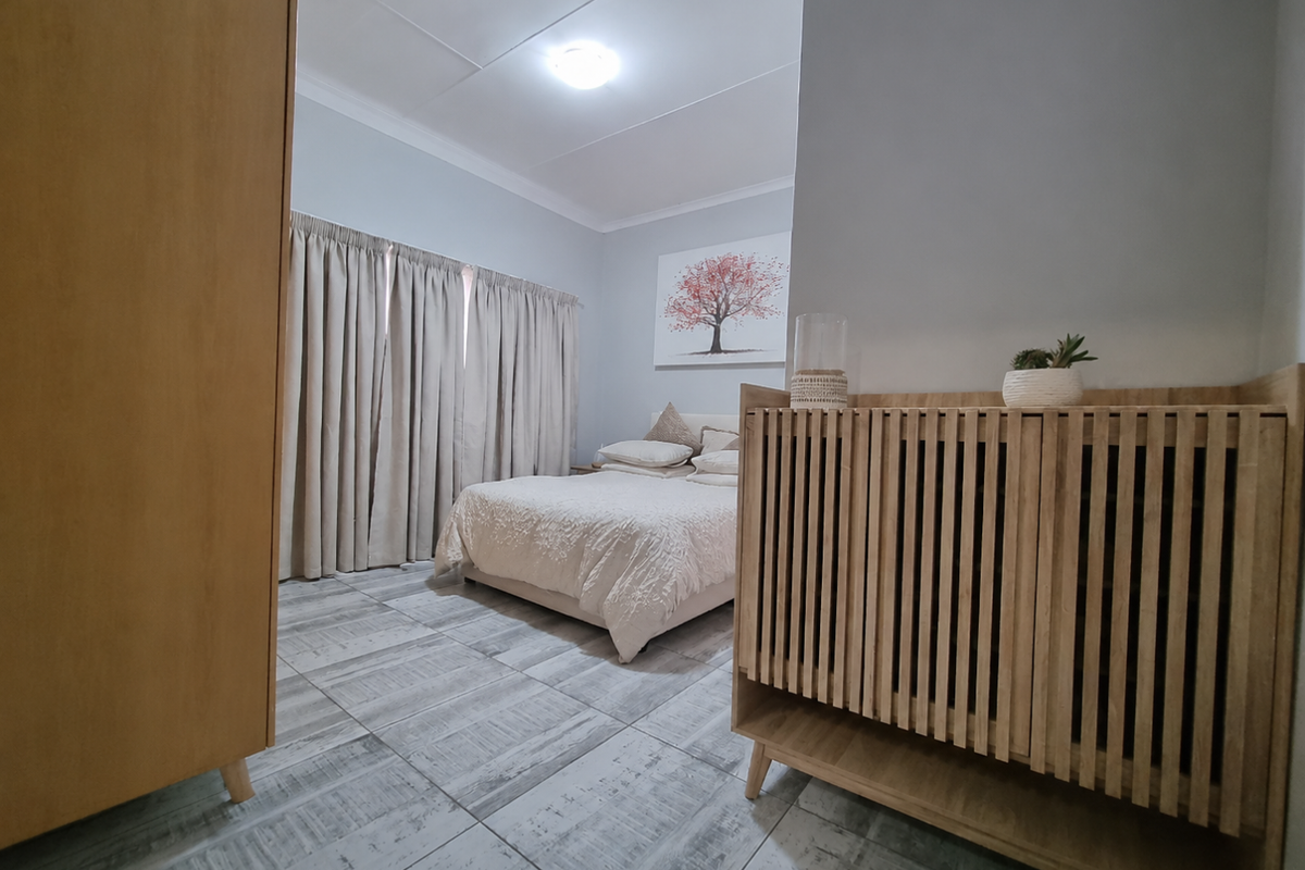 A well-maintained bedroom featuring tiled flooring, neutral wall tones, and floor-to-ceiling curtains, providing a clean and comfortable living space.