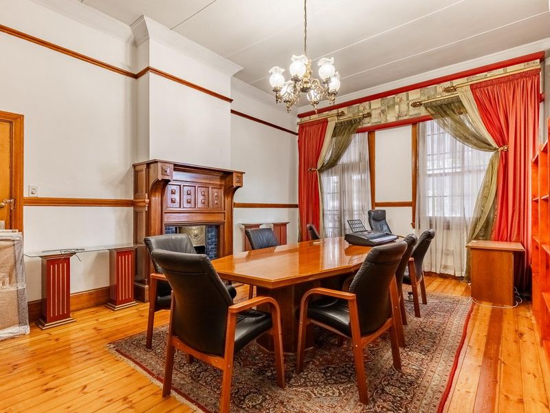 A classic office space featuring polished hardwood floors, a decorative timber fireplace mantel, crown molding, and built-in shelving.