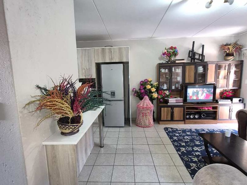 Open plan living area featuring tiled flooring and a compact kitchen space with built-in cabinetry.