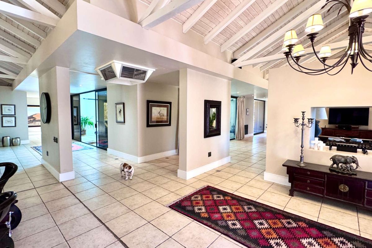 Spacious living area featuring high vaulted ceilings with exposed timber beams, tiled flooring, and a built-in wall niche, creating an open and airy atmosphere.