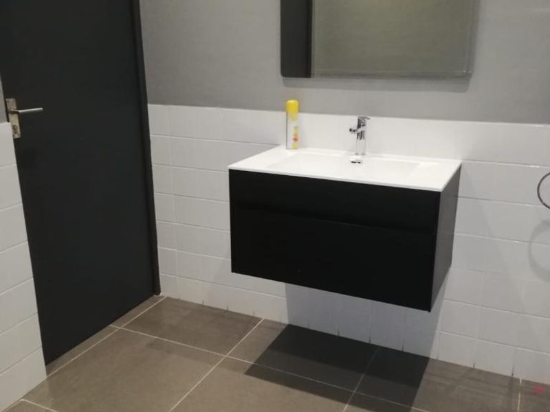 A modern, minimalist bathroom featuring a sleek wall-mounted vanity with an integrated basin, complemented by neutral wall and floor tiling.