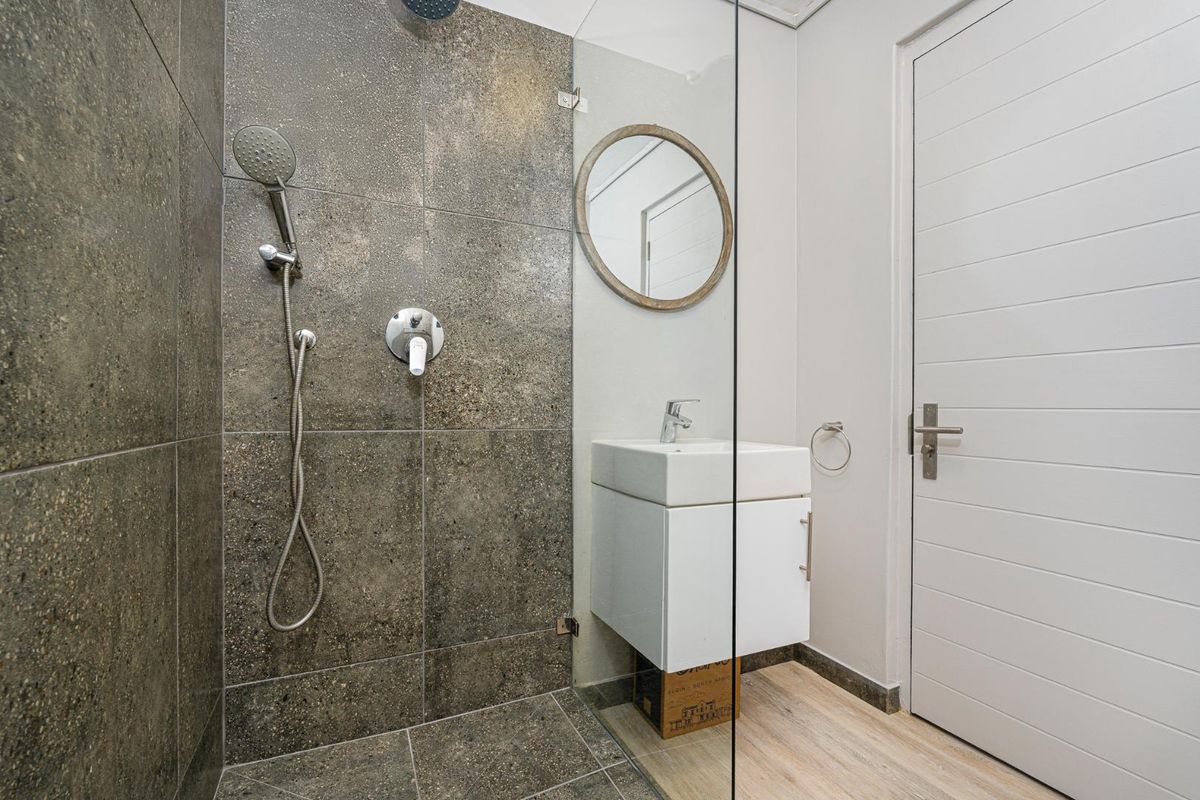 Modern bathroom featuring a walk-in shower with dark textured tiling, a wall-mounted vanity basin, and a glass shower screen.