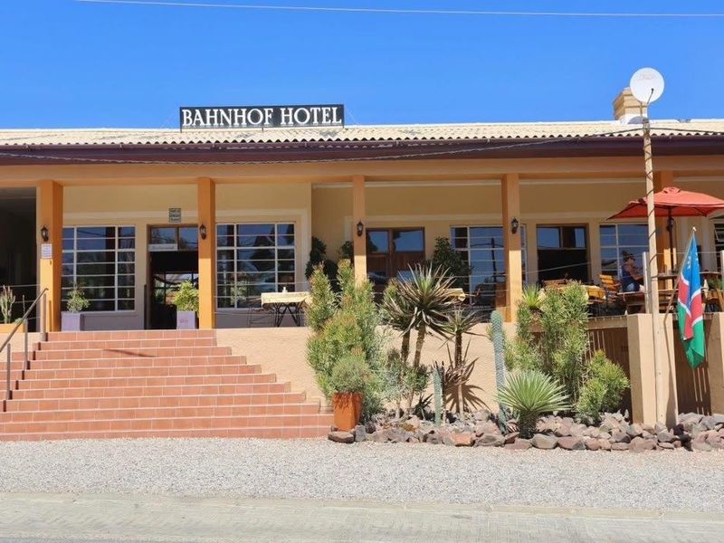 Front elevation of the Bahnhof Hotel featuring a tiled staircase leading to a covered veranda with large windows and exterior signage.