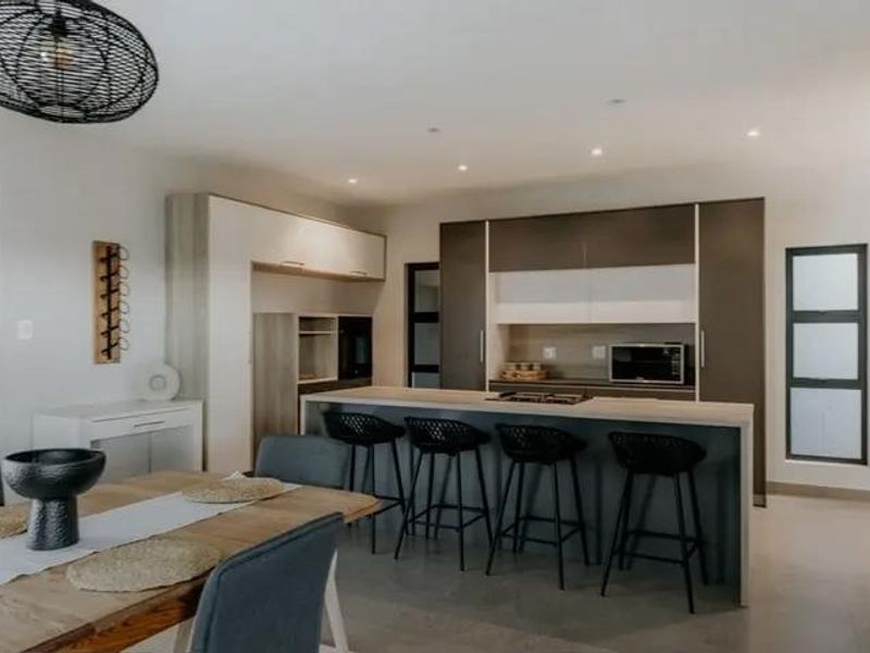 Modern open-plan kitchen and dining area featuring a central island with a gas cooktop, sleek cabinetry, and contemporary recessed lighting.