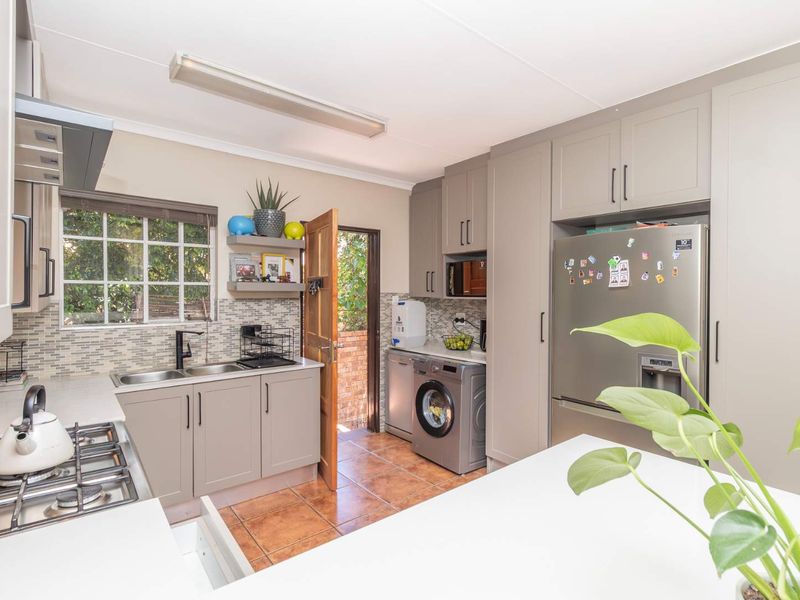 A functional kitchen featuring grey cabinetry, a gas hob, tiled backsplash, and direct access to an outdoor area.