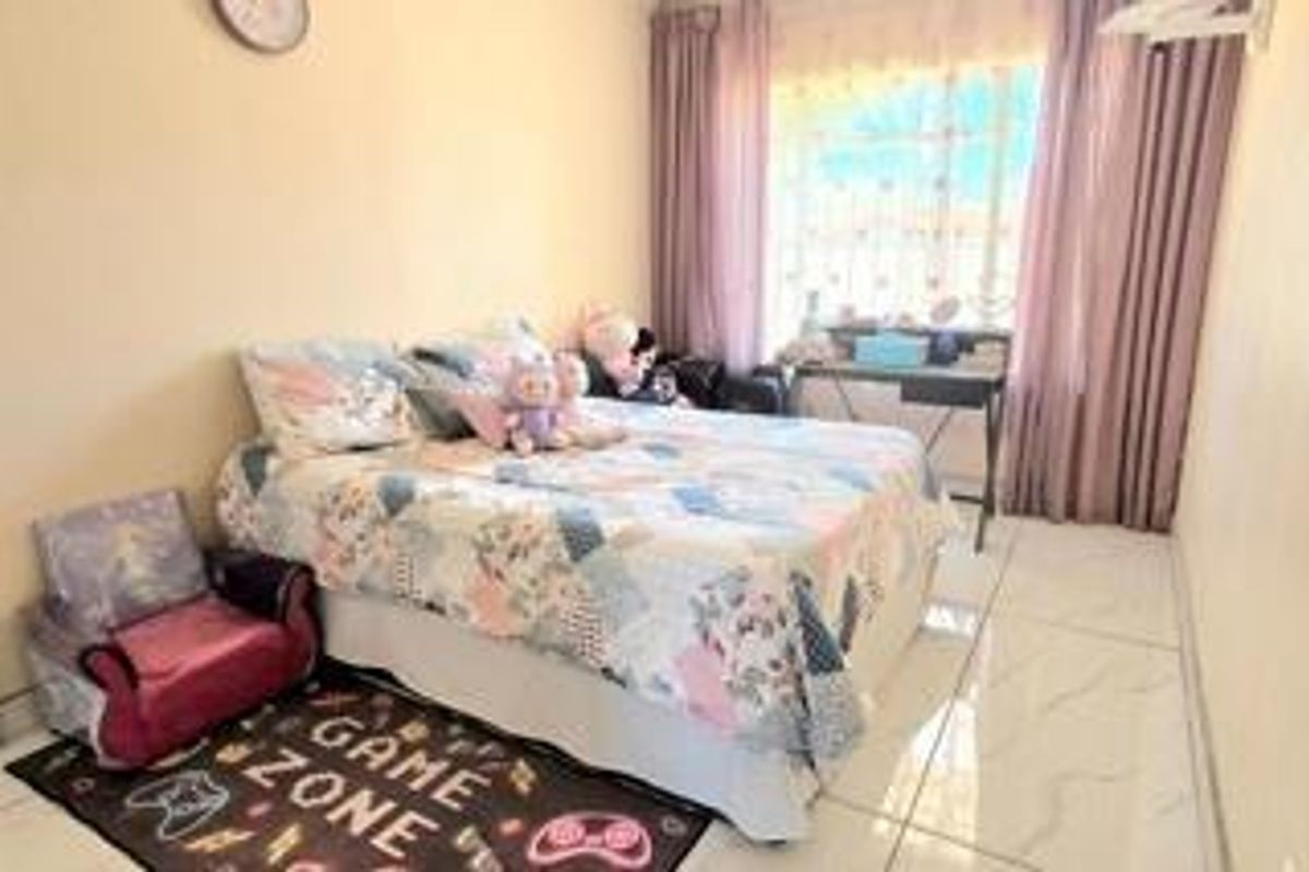 A bedroom featuring tiled flooring and large windows with installed curtain rails, providing a functional living space.