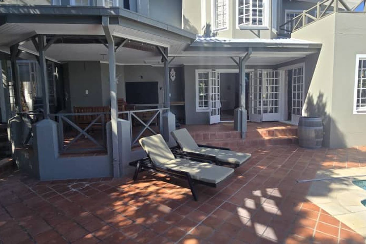 A spacious rear patio area featuring terracotta tiling, a covered entertainment section, and direct access to the swimming pool.