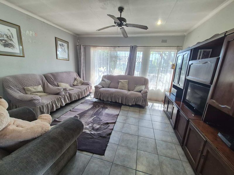 A spacious living room featuring tiled flooring, a ceiling fan, and large sliding glass doors that provide natural light and access to the exterior.
