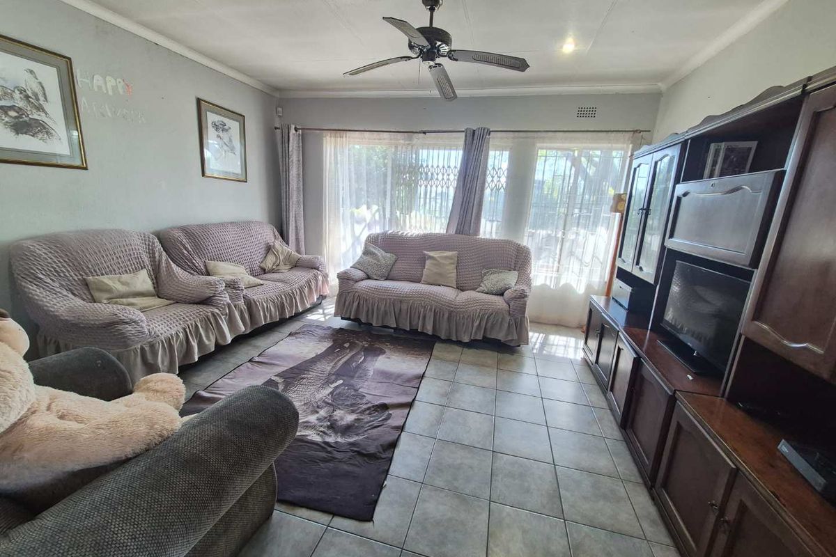 A spacious living room featuring tiled flooring, a ceiling fan, and large sliding glass doors that provide natural light and access to the exterior.