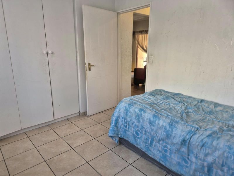 A bedroom featuring tiled flooring and built-in cupboards, requiring minor cosmetic updates to improve its overall appearance.