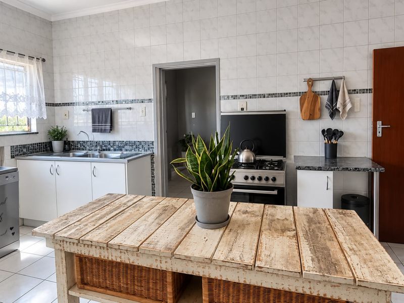 A functional kitchen featuring tiled walls, built-in cabinetry, a gas stove, and a stainless steel sink with tiled flooring throughout.