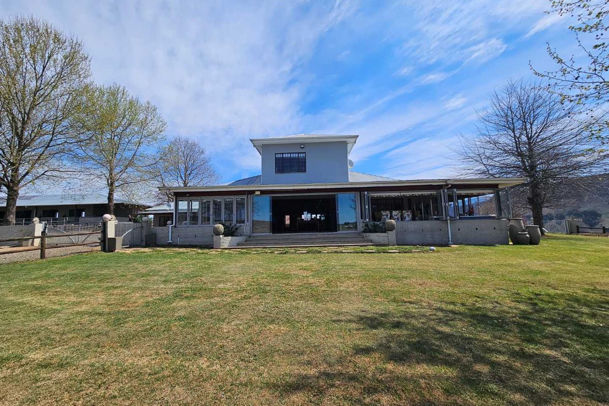 Rear view of a farm property featuring a spacious lawn, covered patio area with large sliding glass doors, and a multi-level roof structure.