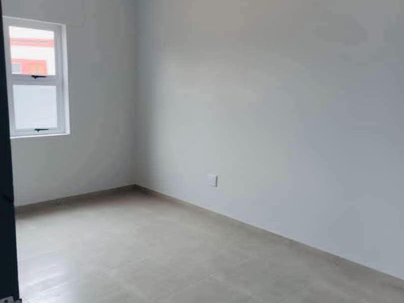 A clean, empty bedroom featuring neutral grey tiled flooring and light-colored walls, providing a blank canvas for personalization.