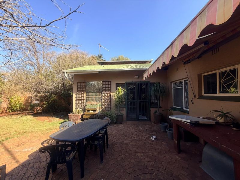A rear patio area featuring brick paving, a retractable awning, and direct access to the garden through a security gate.