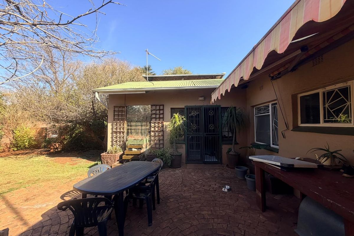 A rear patio area featuring brick paving, a retractable awning, and direct access to the garden through a security gate.