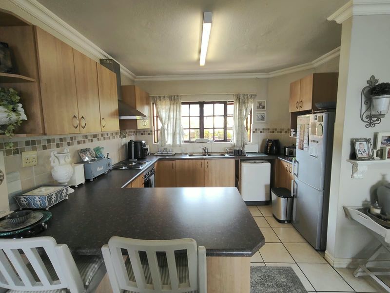 A functional kitchen featuring laminate cabinetry, dark countertops, a double basin sink, and built-in cooking appliances with tiled flooring and backsplash.