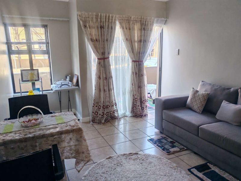 A bright living room featuring tiled flooring and a sliding glass door that provides access to an outdoor balcony area.