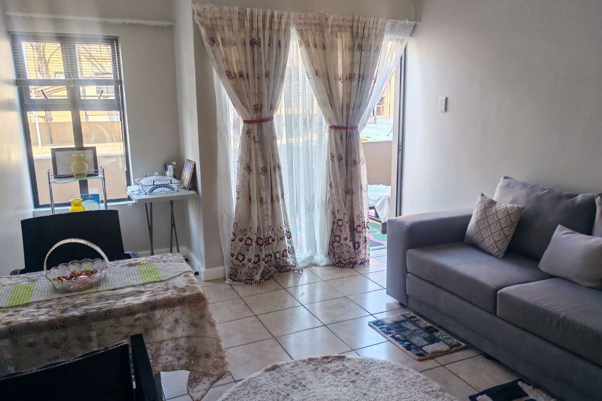 A bright living room featuring tiled flooring and a sliding glass door that provides access to an outdoor balcony area.
