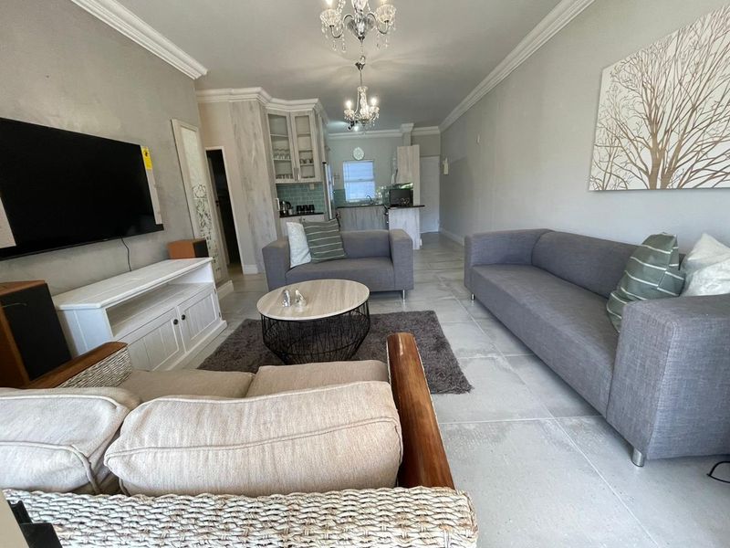 An open-plan living and kitchen area featuring tiled flooring, crown molding, and classic cabinetry, creating a cohesive and functional living space.