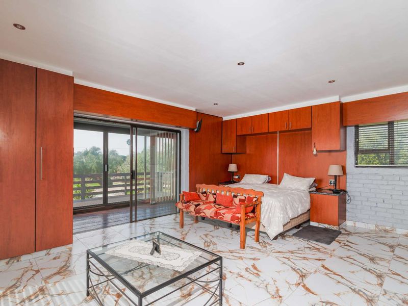 Spacious bedroom featuring extensive built-in cabinetry, marble-look tiled flooring, and sliding glass doors providing access to an outdoor balcony area.