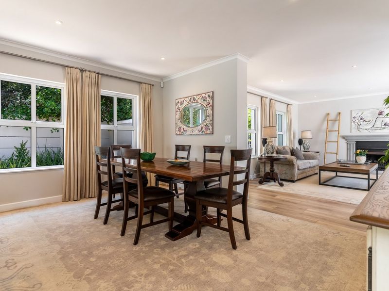 Spacious open-plan living and dining area featuring timber flooring, recessed lighting, and a classic fireplace, creating a bright and inviting atmosphere.