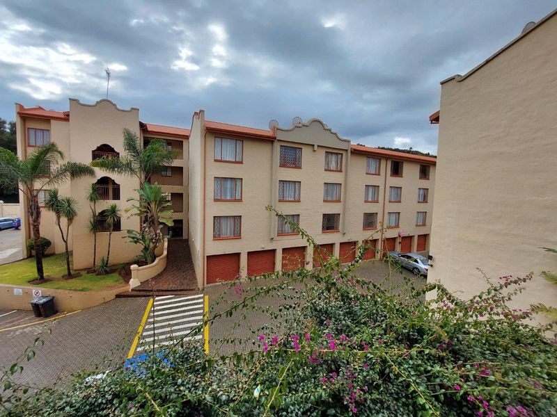Exterior view of a multi-story apartment complex featuring paved driveway access, integrated garage doors, and balcony access for upper-level units.