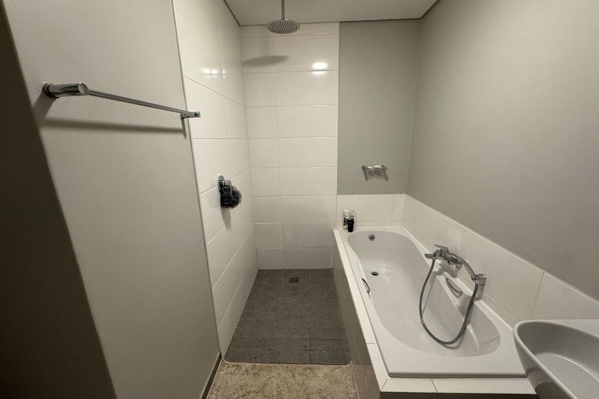 A modern bathroom featuring a built-in bathtub, a separate walk-in shower area with tiled finishes, and a wall-mounted towel rail.