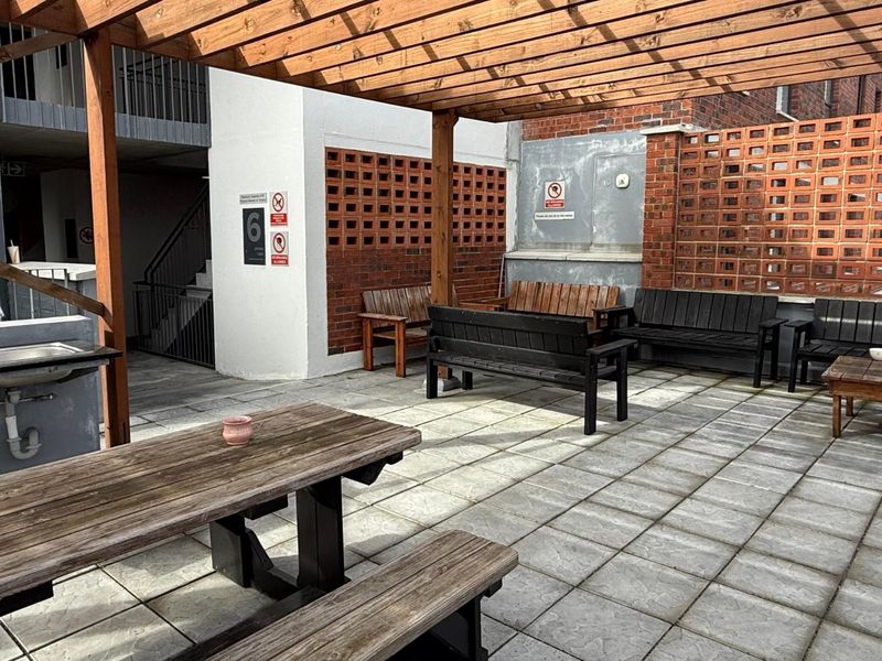 Outdoor patio area featuring a wooden pergola, paved flooring, brick breeze block walls, and a built-in sink station.