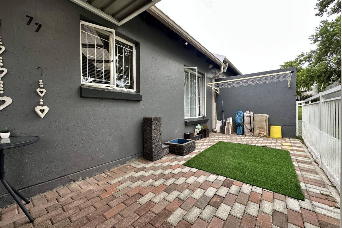A private rear courtyard featuring paved flooring, a small artificial grass section, and a wall-mounted retractable clothesline.