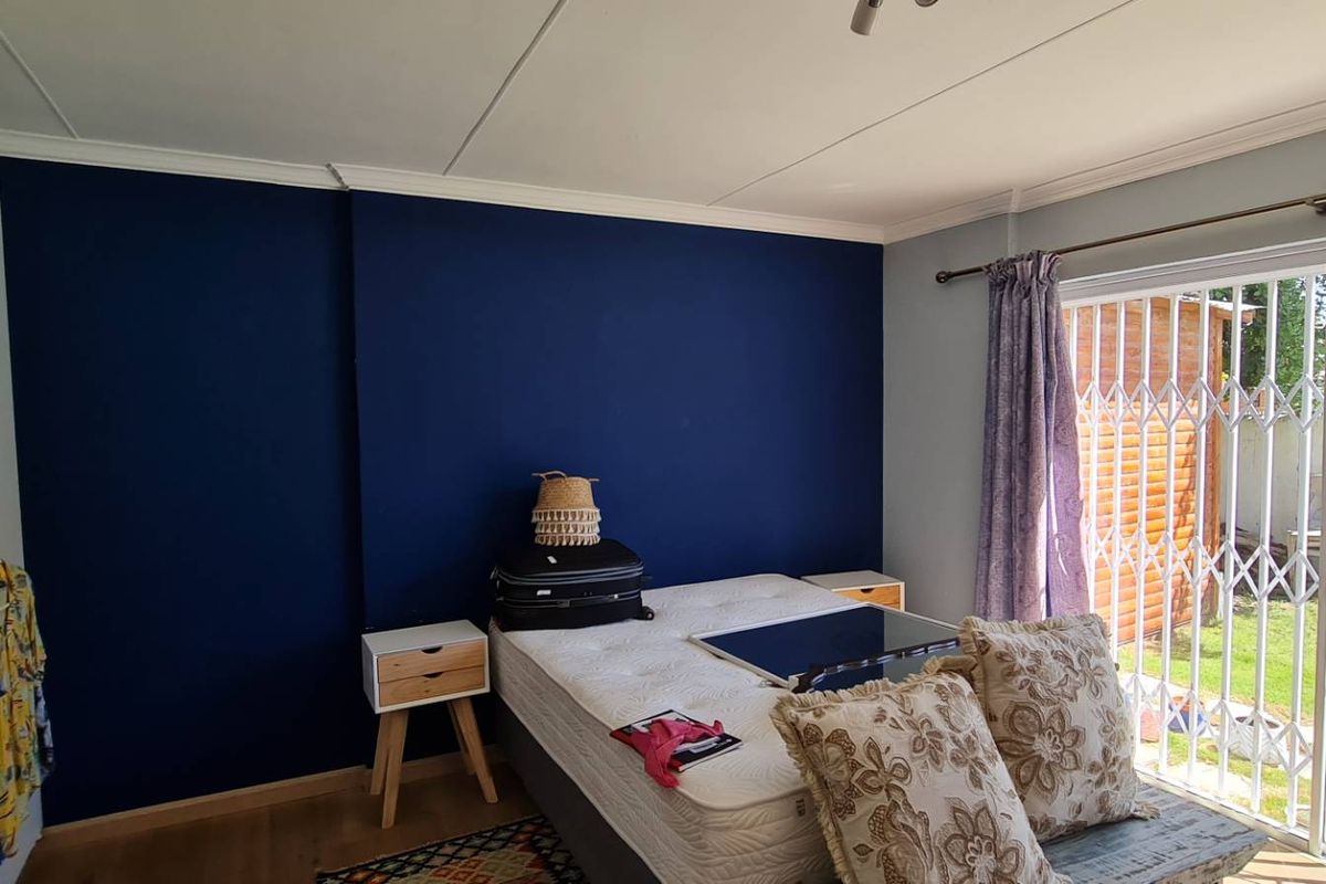 Bedroom featuring laminate flooring, built-in cupboards, and a sliding glass door with a security gate providing direct access to the garden.
