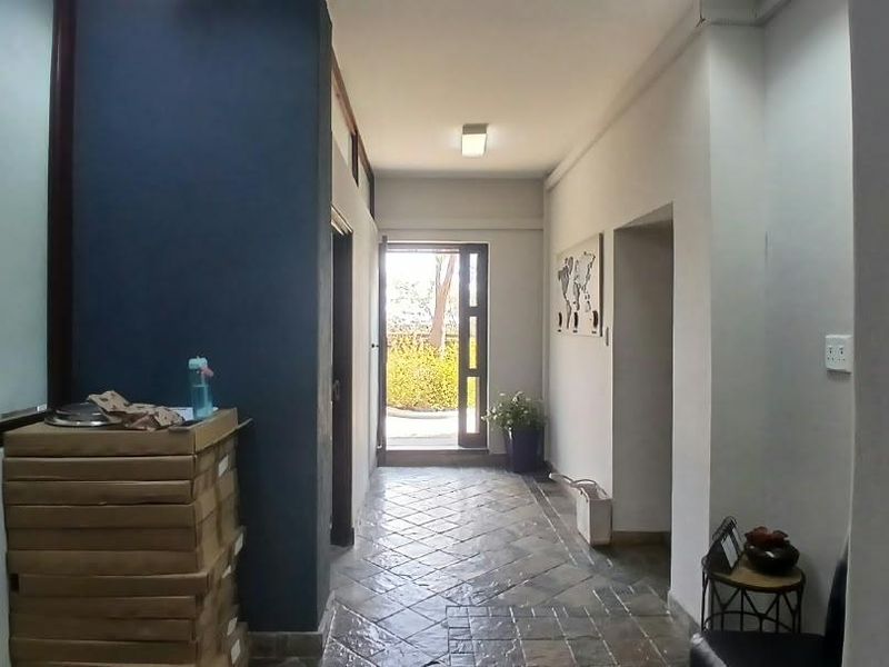 A functional office hallway featuring tiled flooring, recessed lighting, and a glass-paneled door leading to an outdoor area.