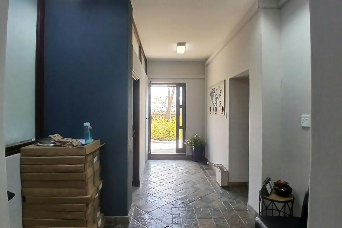 A functional office hallway featuring tiled flooring, recessed lighting, and a glass-paneled door leading to an outdoor area.
