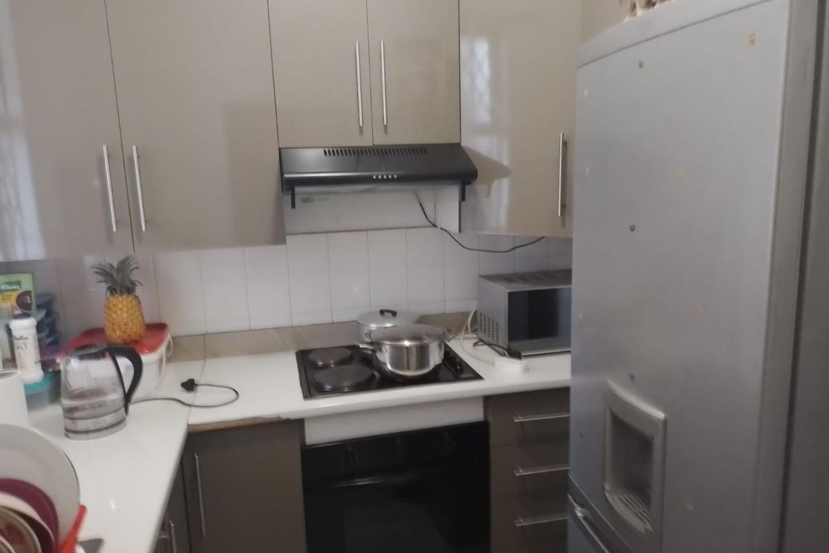 Compact kitchen featuring modern high-gloss cabinetry, built-in oven, electric hob, extractor fan, and tiled backsplash with ample counter space.