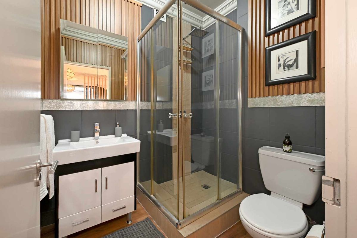 Modern bathroom featuring a glass shower enclosure, vanity unit with basin, and contemporary wall paneling finishes.