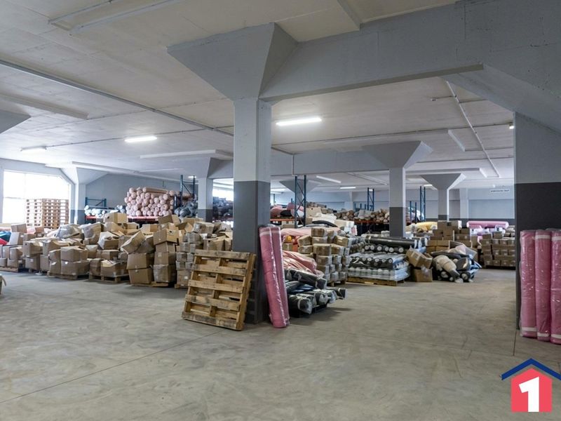 Spacious industrial warehouse area featuring concrete flooring, structural support columns, and overhead fluorescent lighting, suitable for storage or manufacturing operations.