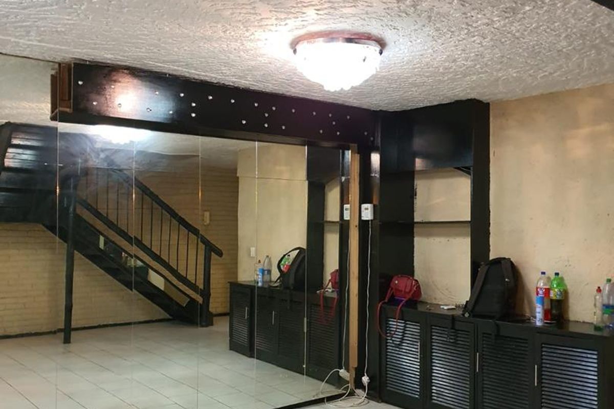 A multi-purpose room featuring large wall-to-wall mirrors, built-in storage cabinetry, tiled flooring, and an internal staircase leading to the upper level.