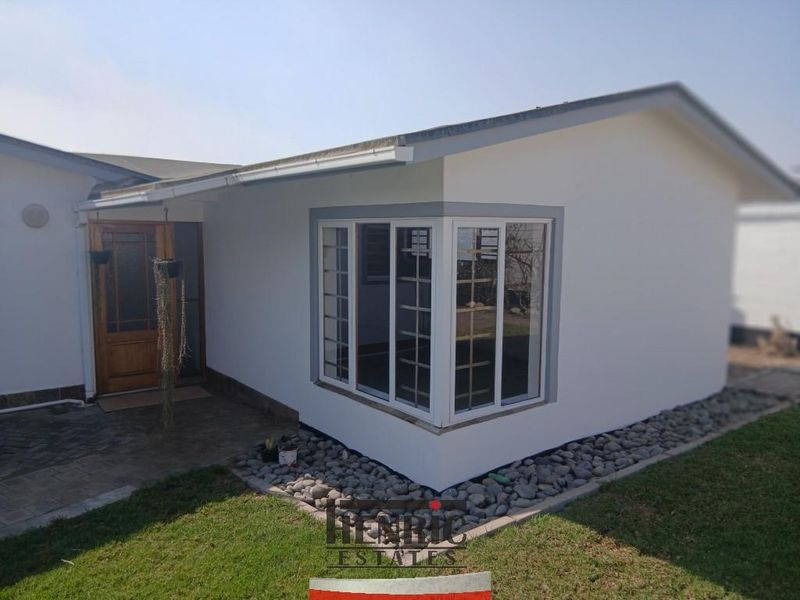 Front elevation of the house featuring a prominent bay window, timber entrance door, and neat pebble landscaping along the paved walkway.
