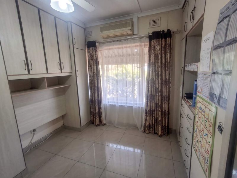 A bedroom featuring extensive built-in cabinetry, a built-in desk, tiled flooring, and an integrated air conditioning unit.