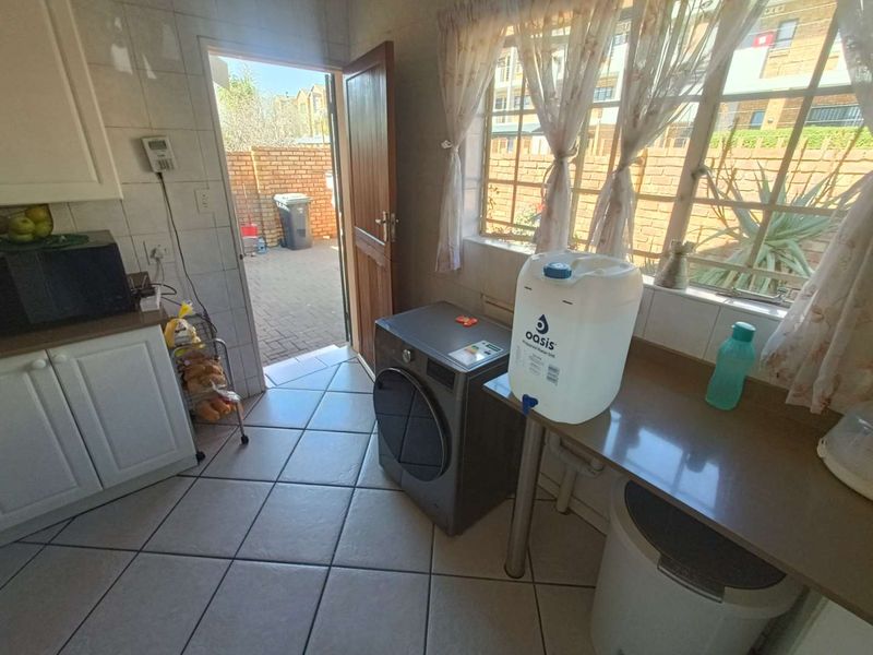 A functional scullery area featuring tiled flooring, built-in cabinetry, and direct access to the rear exterior patio.