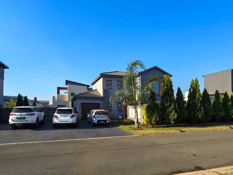Front elevation of a modern two-story residential house featuring a paved driveway, garage, and landscaped garden area.