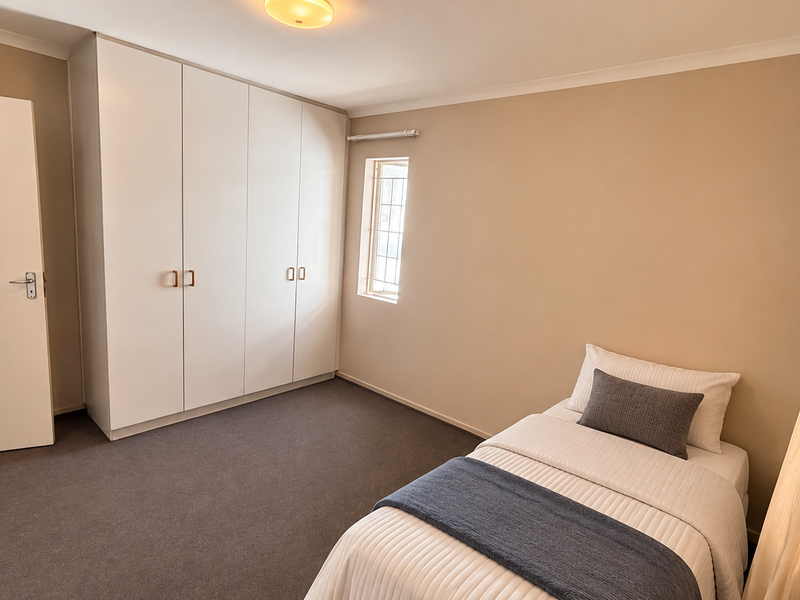 A well-maintained bedroom featuring neutral walls, carpeted flooring, and ample built-in cupboard storage space.