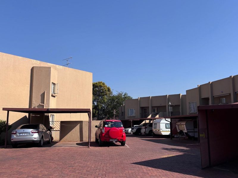 Exterior view of an apartment complex featuring paved parking areas and covered carport structures for residents.