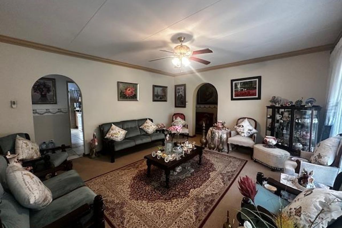 A spacious living room featuring arched doorways, a central ceiling fan, and neutral wall finishes, providing a comfortable and traditional living environment.