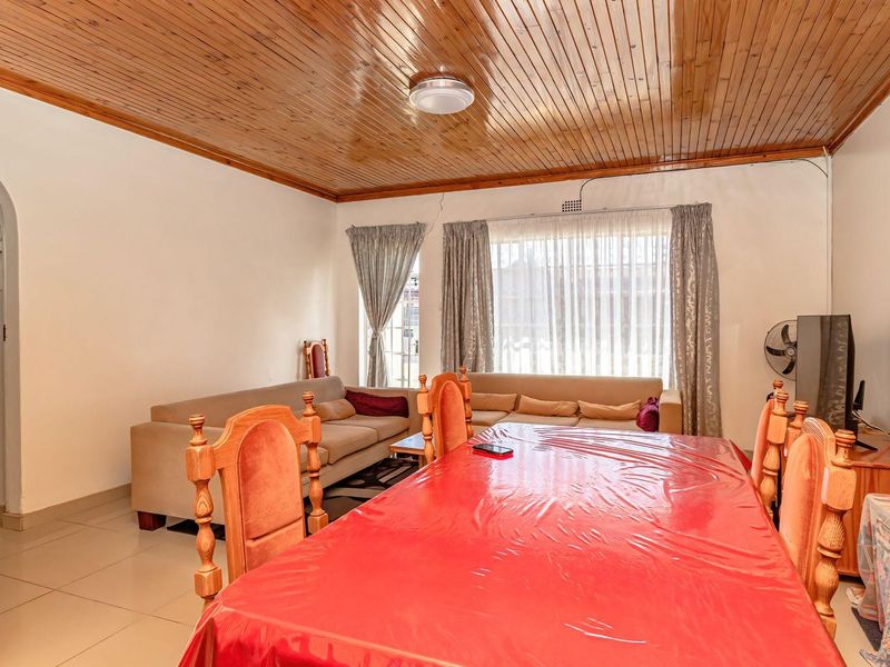 Open plan living and dining area featuring a distinctive timber tongue and groove ceiling and tiled flooring.