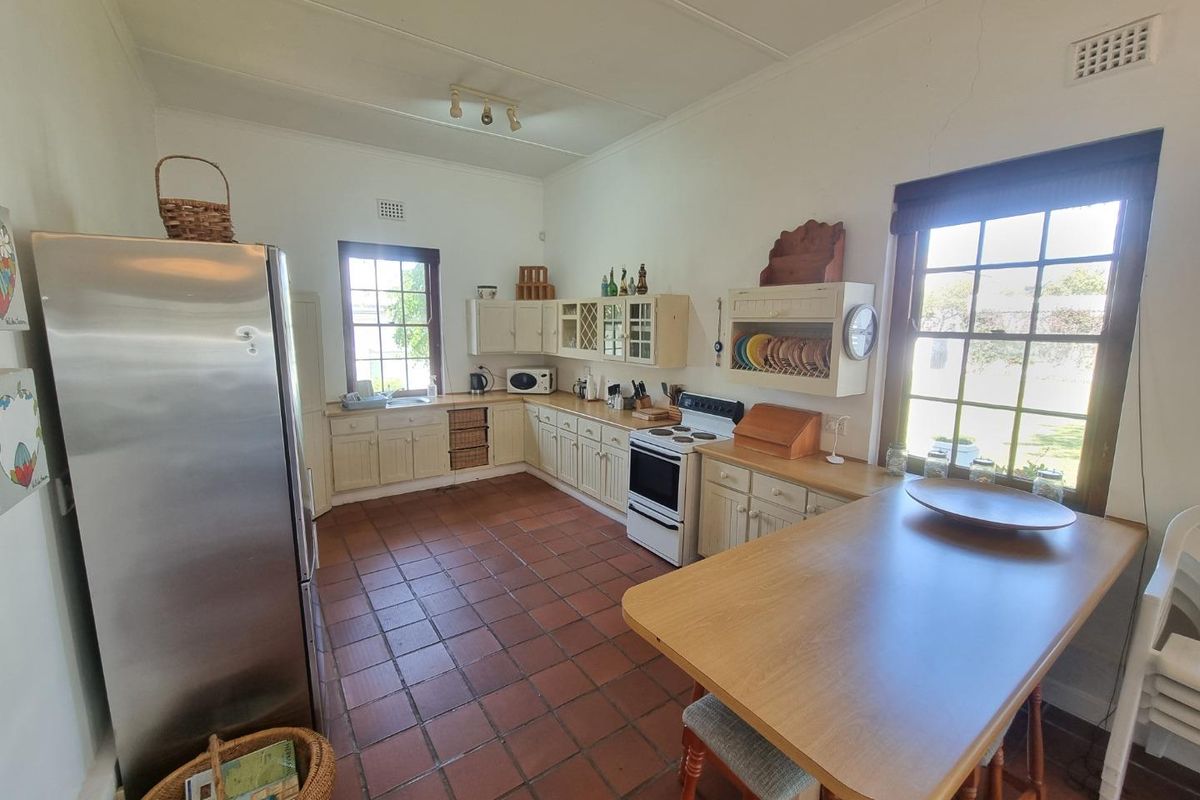 A functional kitchen featuring traditional cabinetry, terracotta floor tiles, and a breakfast bar, offering a classic layout with ample natural light.