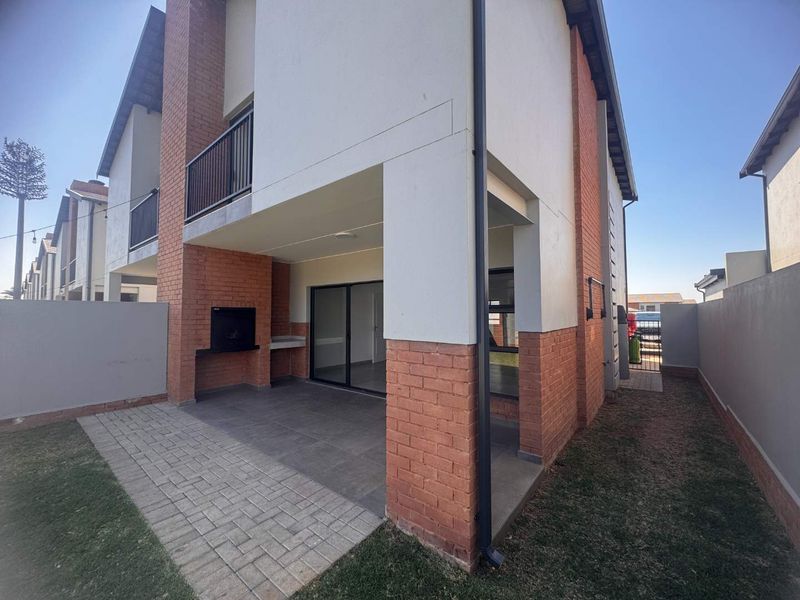 Covered patio area featuring a built-in braai, brick detailing, and sliding door access to the interior living space.