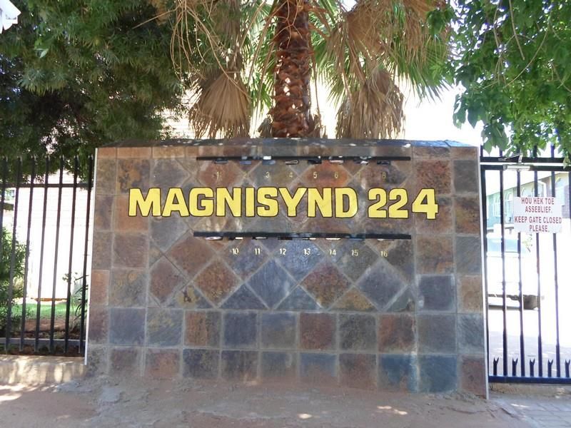 Front entrance view of the Magnisynd 224 apartment complex, featuring a stone-clad boundary wall with integrated mailboxes and a secure metal gate.