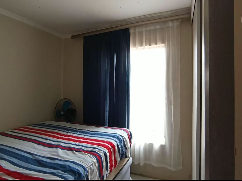 A standard bedroom featuring a built-in wardrobe and a window with installed curtain rods.