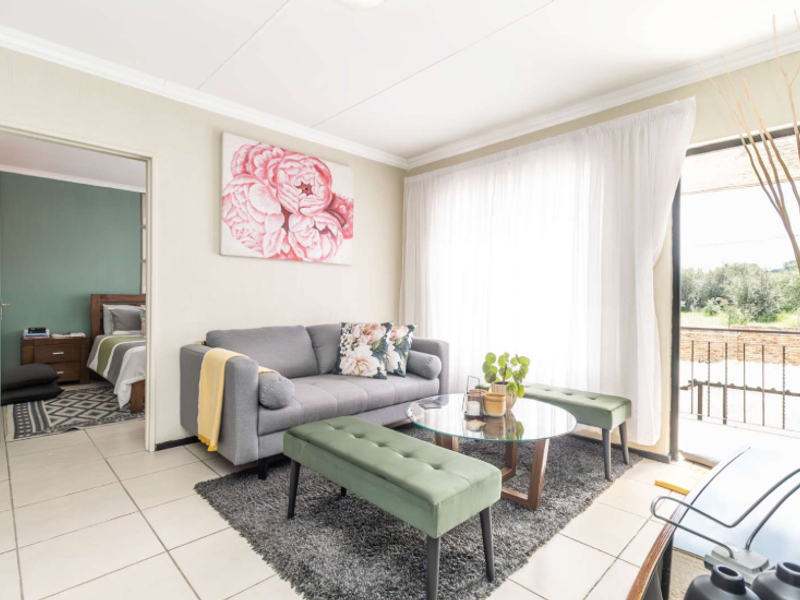 A bright living room featuring tiled flooring, coved ceilings, and a sliding glass door providing access to an outdoor balcony area.